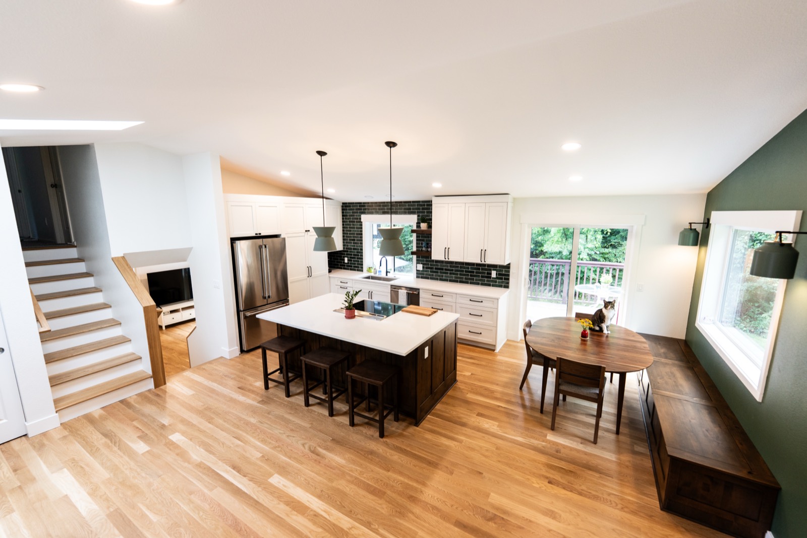Open-concept kitchen remodel with green tile and pendant lighting